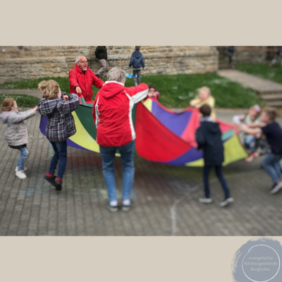 Das Bild zeigt Erwachsene und Kinder mit einem Schwungtuch.